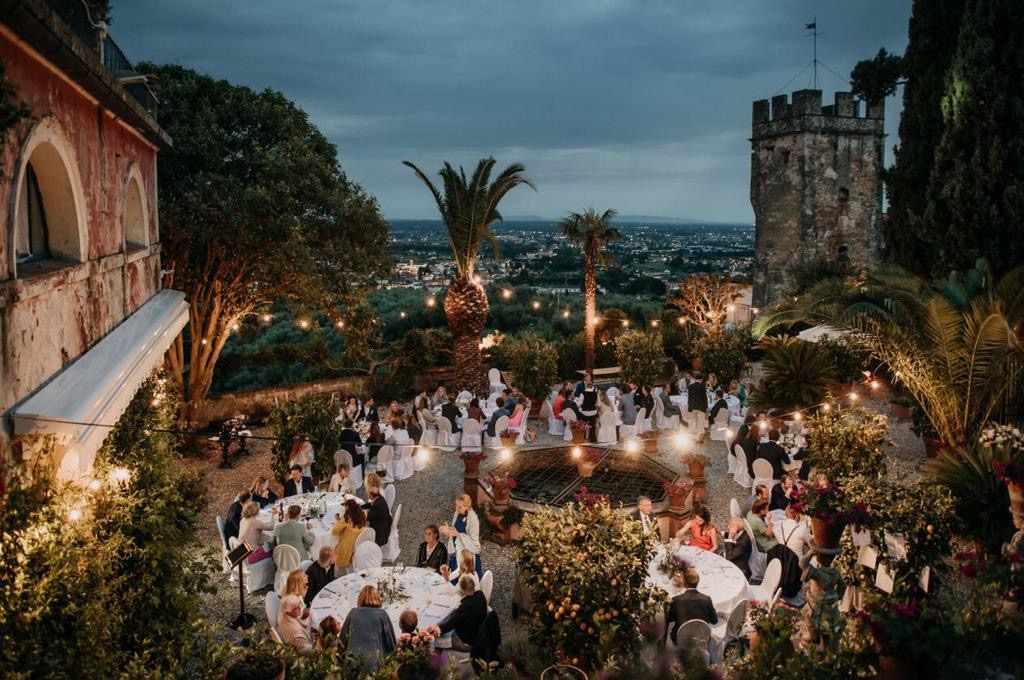 Evening wedding reception on the terrace at Villa Sermolli: string lights, banquet tables and a view over the Tuscan valley at dusk